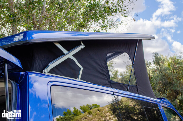 Vista lateral de una Volkswagen T6.1 Caravelle con techo elevable BRAM abierto, tijeras traseras reforzadas, lona y ventanas con mosquitera integrada.