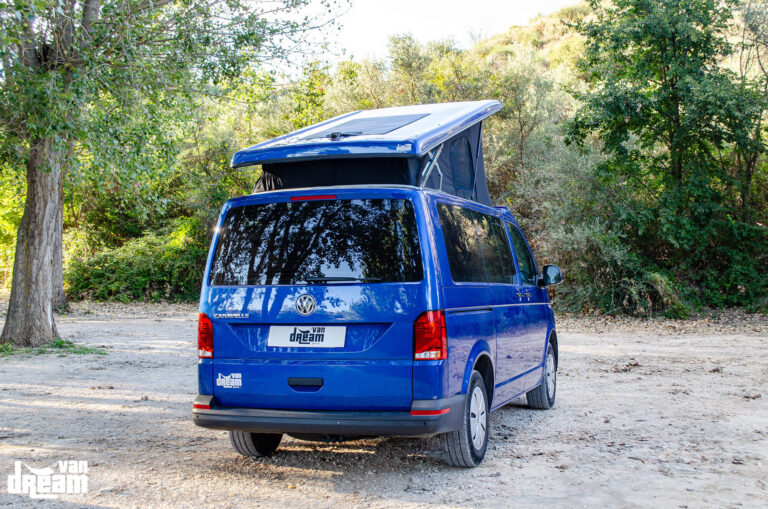 Vista exterior trasera de una Volkswagen T6.1 Caravelle con techo elevable BRAM abierto, mostrando la estructura elevada y la lona del techo desde la parte posterior.