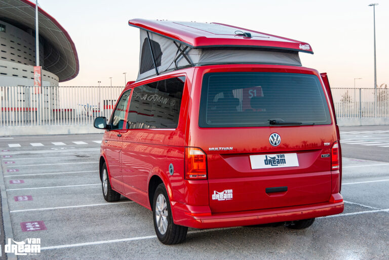 Vista trasera de una Volkswagen T6 Multivan roja con techo elevable Reimo abierto, mostrando la elevación del techo sobre la carrocería.