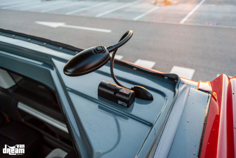 Detalle de la instalación de iluminación LED y toma de corriente de 12 V tipo mechero en el techo elevable Reimo de una Volkswagen T6 Multivan.