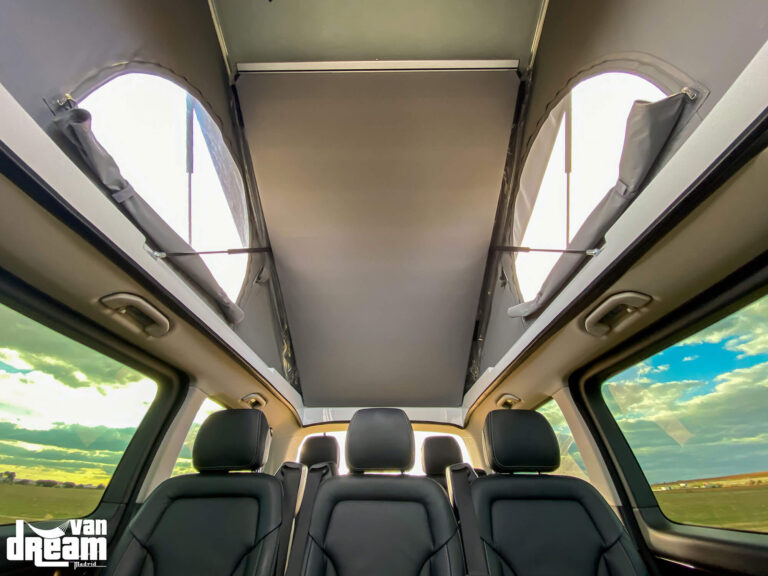 Vista interior de una Mercedes-Benz Clase V L2 con techo elevable SCA y cama superior elevados, mostrando la amplitud del habitáculo y los asientos originales conservados.