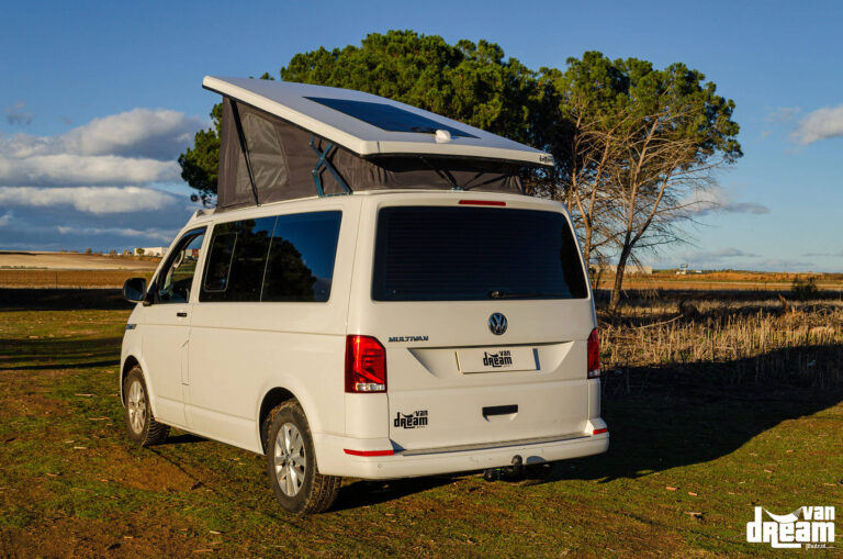 Vista trasera de una Volkswagen T6 Multivan con techo elevable Atlas Camper abierto y placa solar flexible instalada sobre el techo.