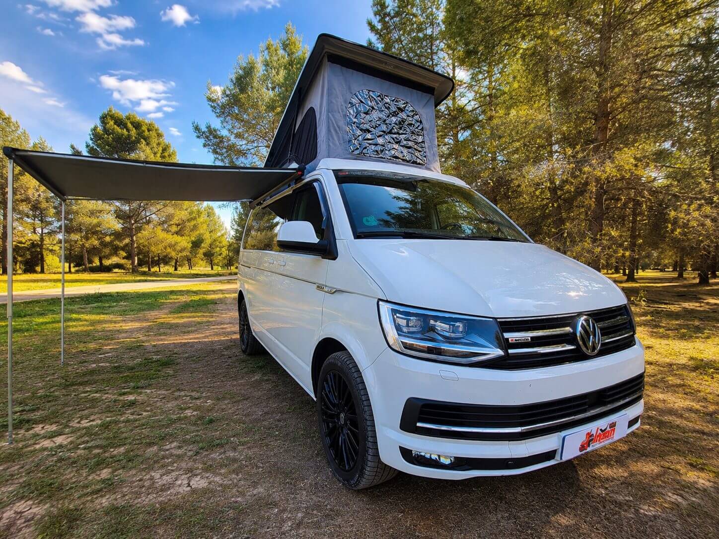 Volkswagen T6 camperizada con techo elevable y toldo lateral en entorno natural preparada para viajar y pernoctar