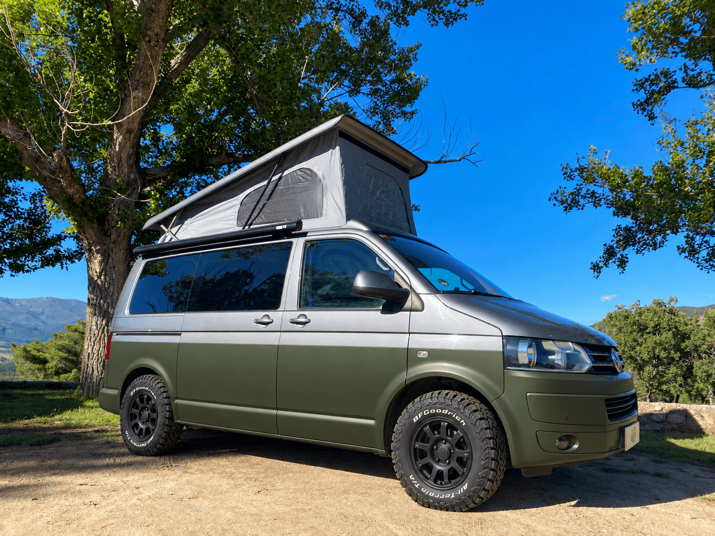 Simulación de Volkswagen camper bicolor gris y verde oliva, con techo elevable y llantas negras